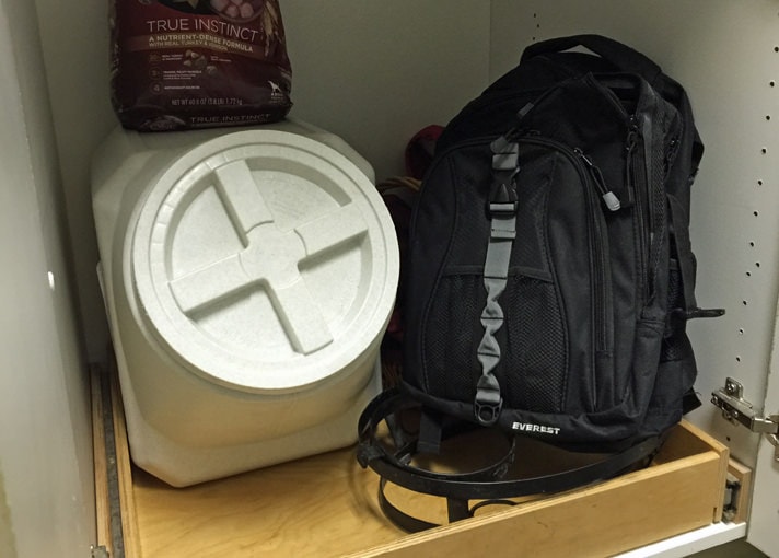 Pet food and book bag stored in a bottom cupboard.