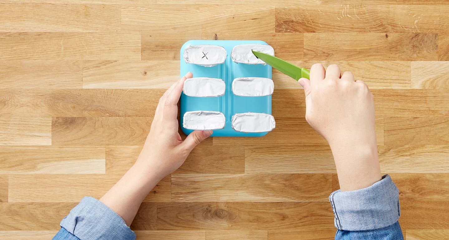 Cover each of the filled plastic molds with aluminum foil and gently cut a small X into the middle using the knife.