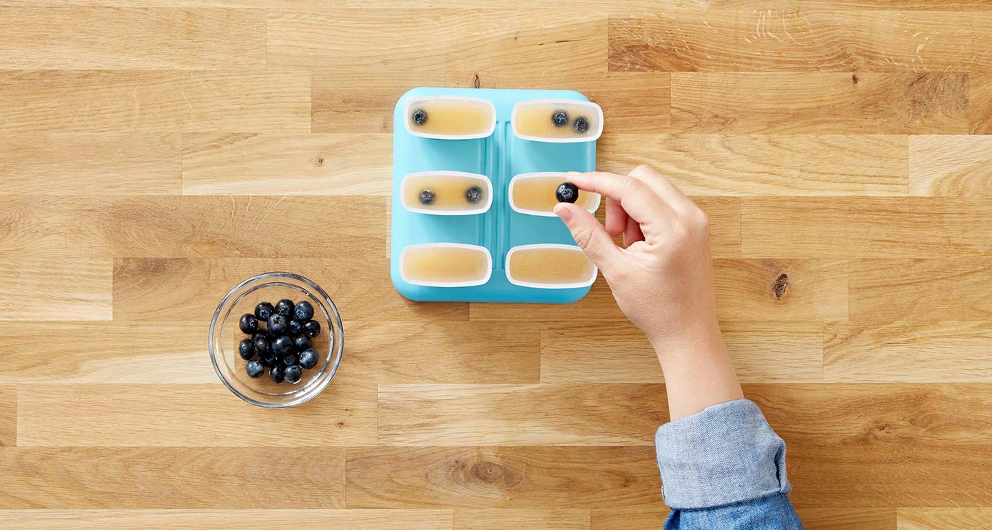 Wash the blueberries and drop 4-5 into each popsicle mold.