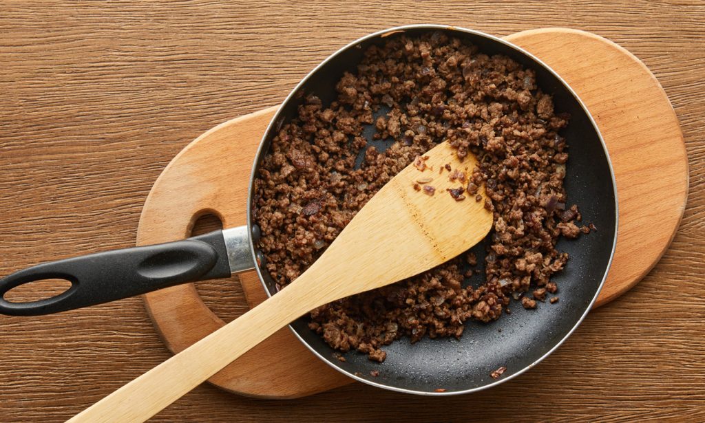 ground beef in pan wooden spoon