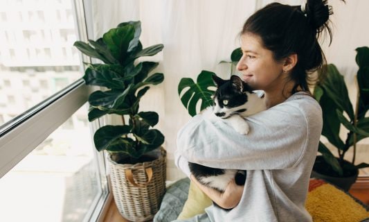 woman with cat looking out window