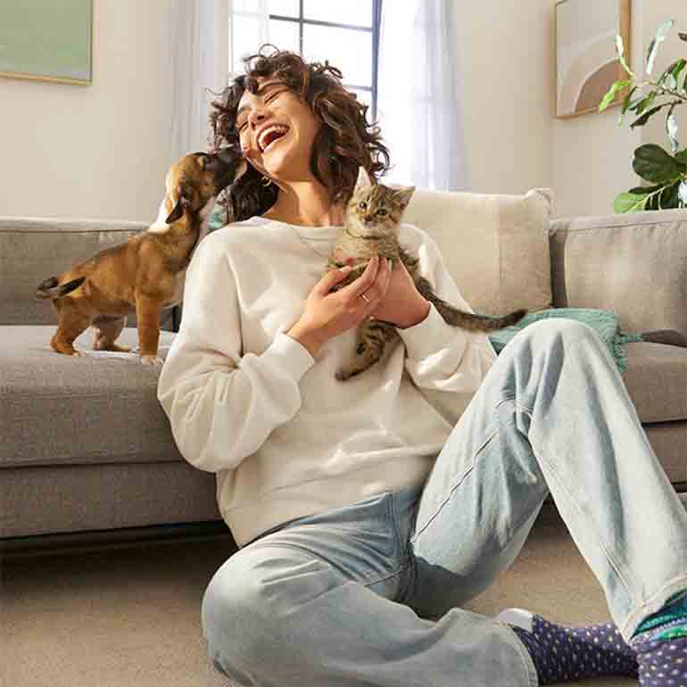 woman laughing with puppy and kitten