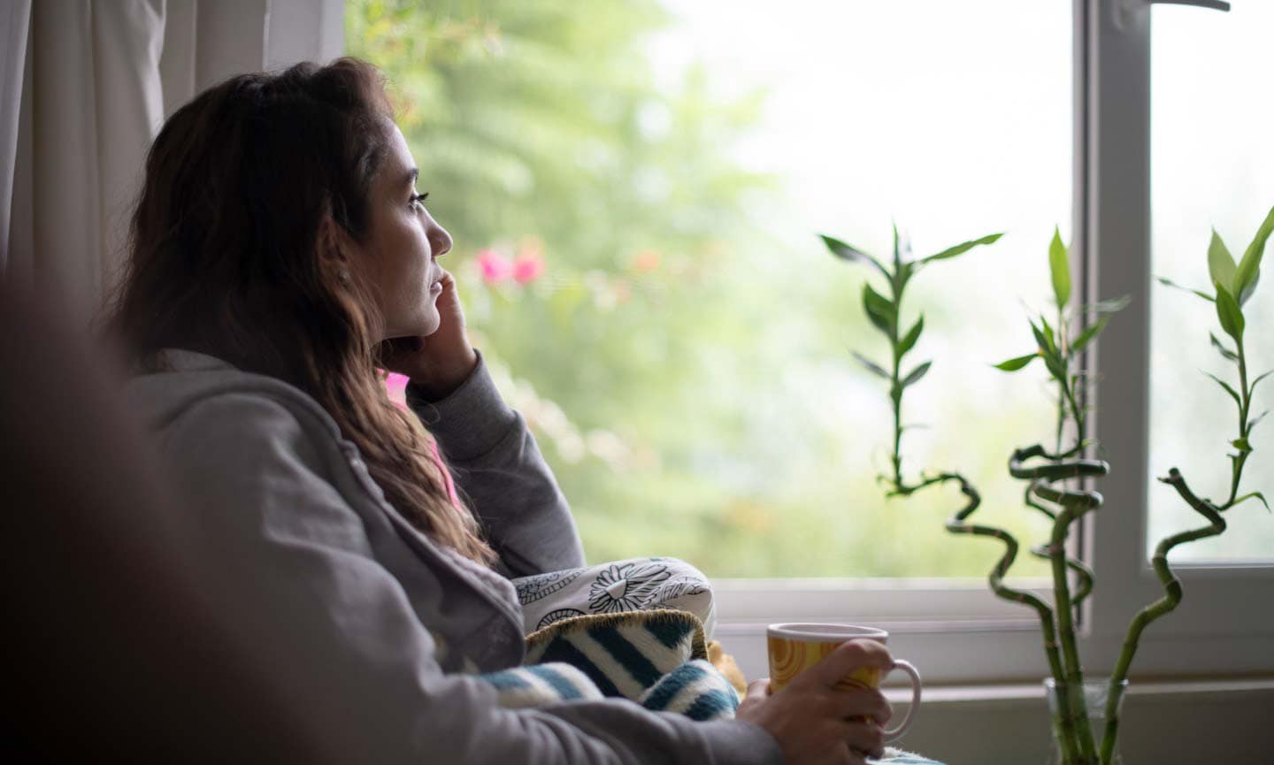 woman sitting at a window with a mug
