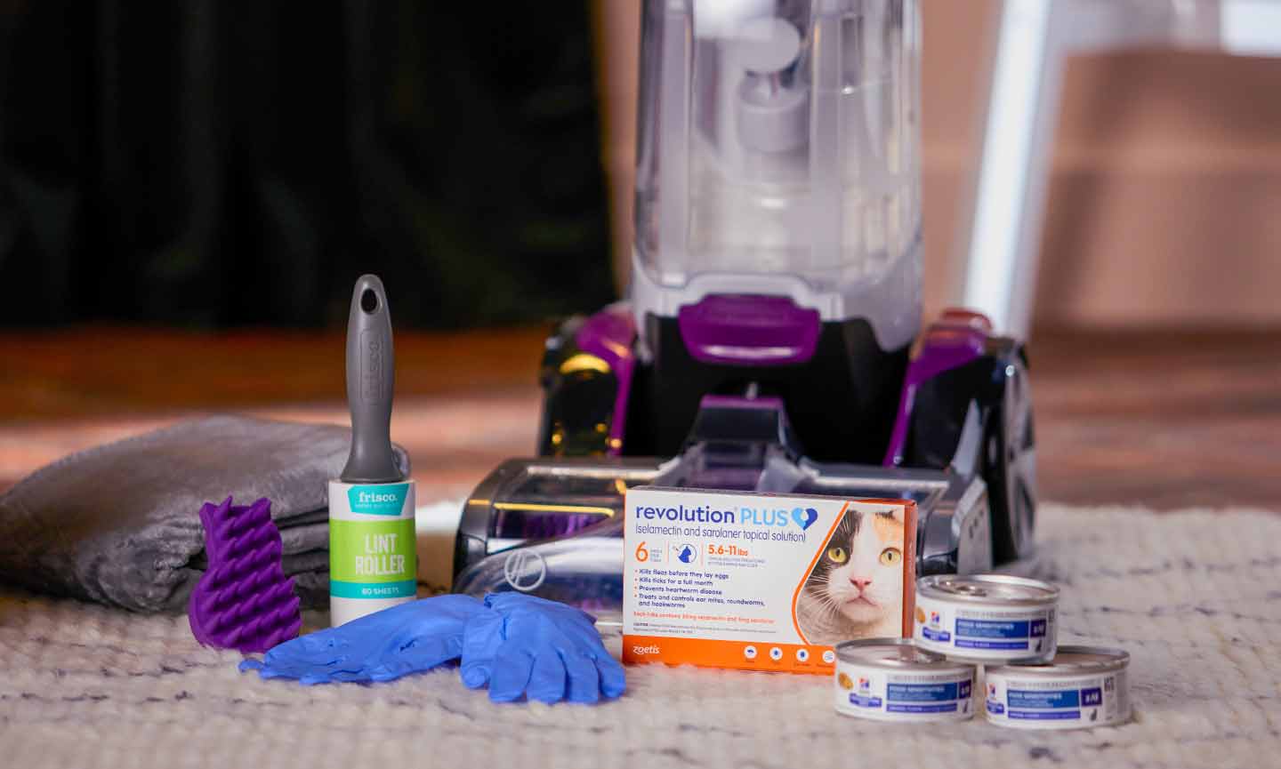 a collection of cat shedding supplies including lint brush, rubber gloves, flea and tick preventative, vacuum cleaner, brush and cat food