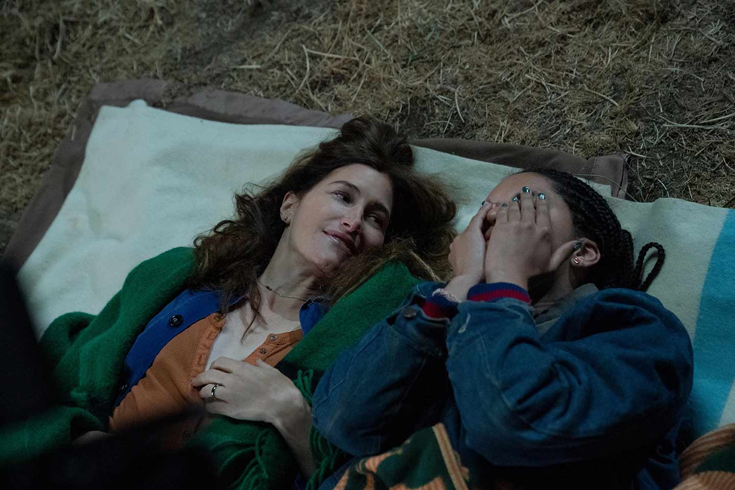 A still from the Hulu series "Tiny Beautiful Things" showing two women laying on a blanket in the grass