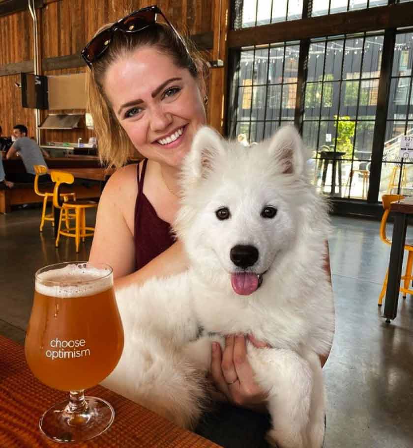 A woman and her dog sitting inside Optimism Brewery
