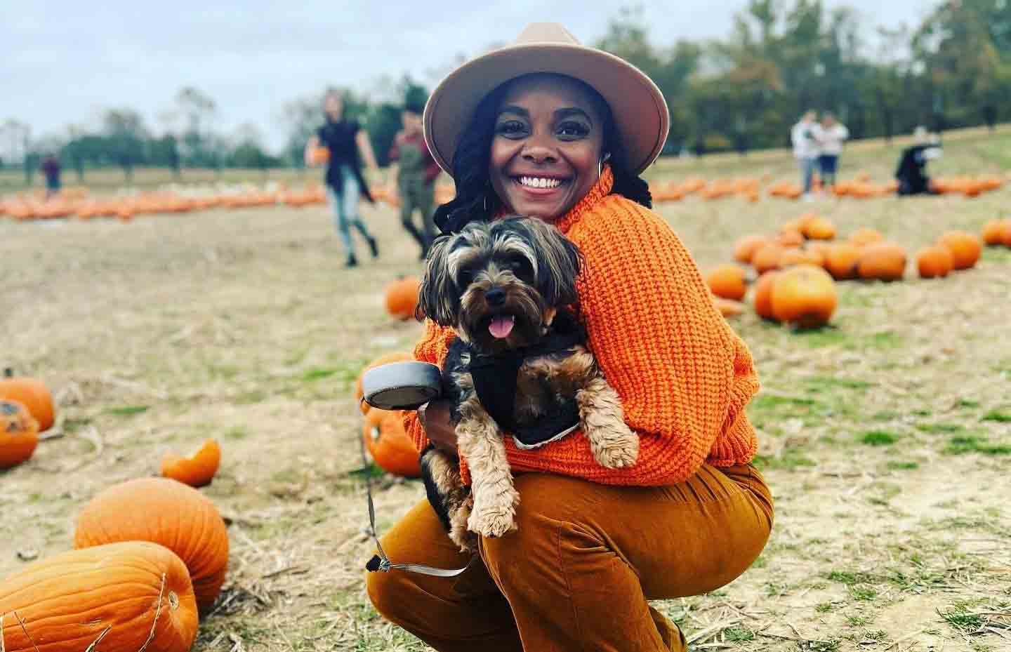 A woman and her dog posing at a pumpkin patch