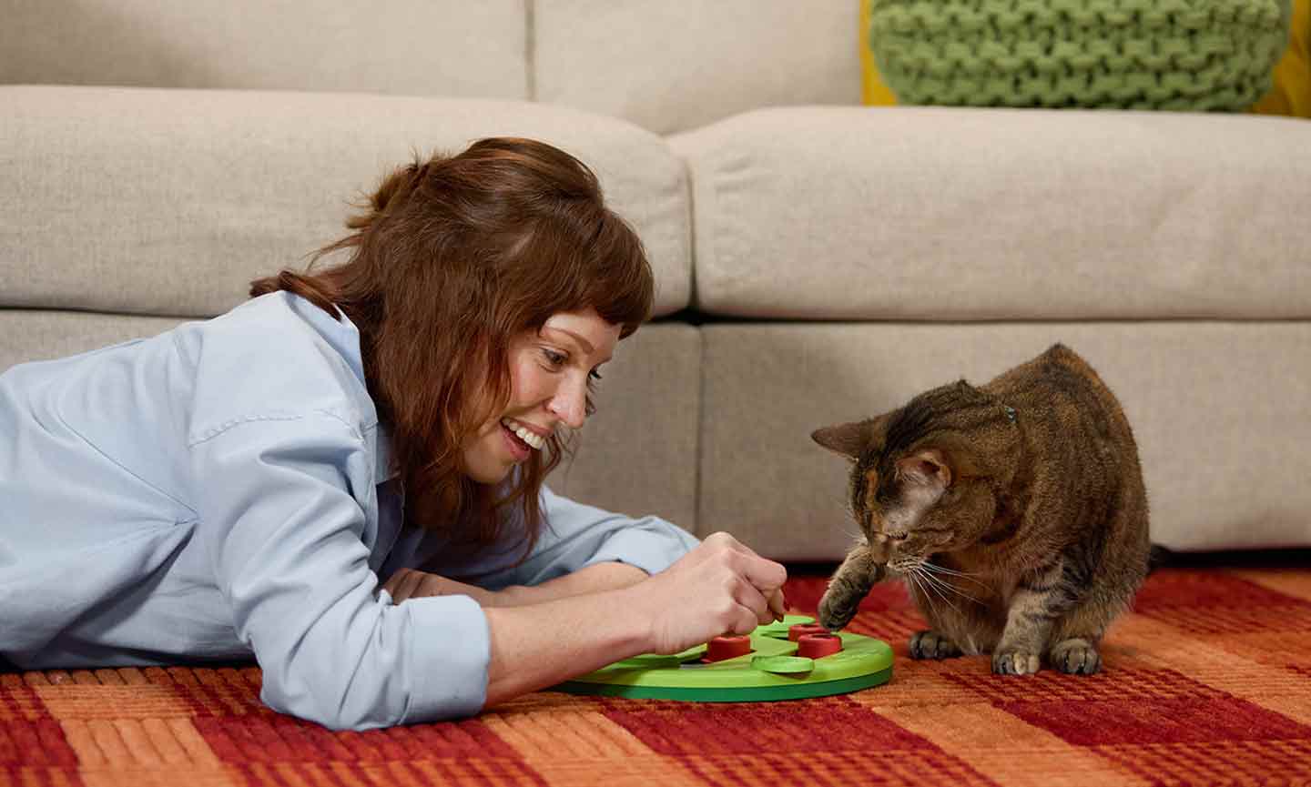 Photo of a woman and her cat playing with a puzzle feeder