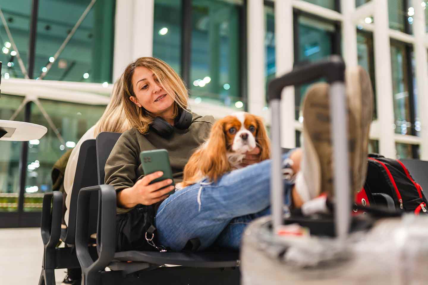 Photo of a woman and her dog sitting in an airport