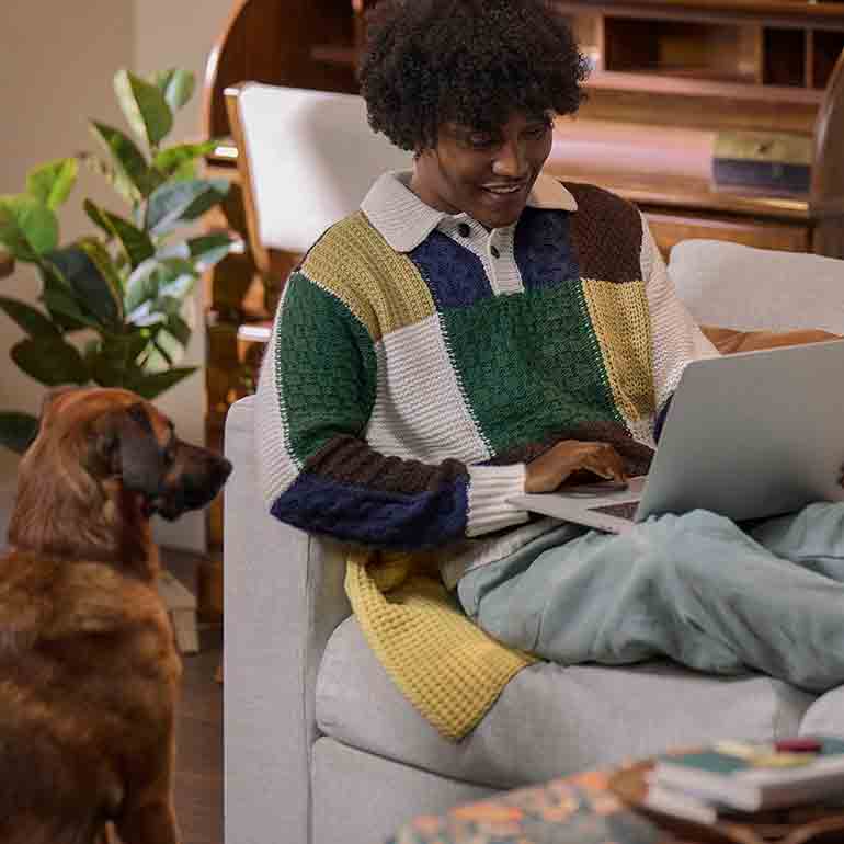 Photo of a man using a laptop computer with his dog beside him